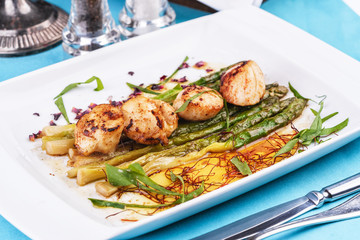  European recipe, Mediterranean dish. Caramelized asparagus with onion chips, rose petals, arugula and pieces of fried fish