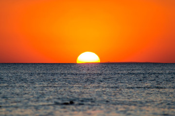 Quiet calm sea against the big setting sun