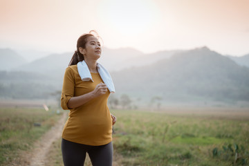 happy asian pregnant woman in her trimester workout outdoor