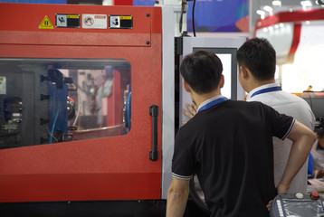 Industrial technician operate plastic injection molding press machine in manufacturing factory