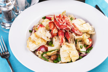  European recipe, Mediterranean dish. Roast vegetables - radish, greens, onions, olives, cabbage, with pasta in a creamy sauce with crab meat and fish pieces.