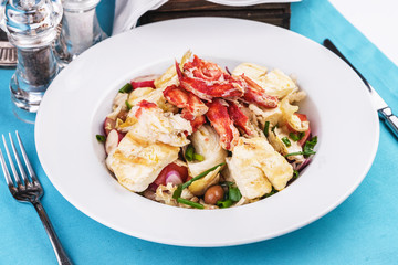  European recipe, Mediterranean dish. Roast vegetables - radish, greens, onions, olives, cabbage, with pasta in a creamy sauce with crab meat and fish pieces.