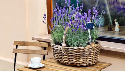 Naklejka premium Lavender flowers in a basket and a cup of coffee on the wooden table