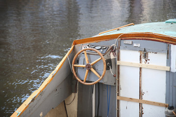Old fisherman motorboat with a steering wheel on a river