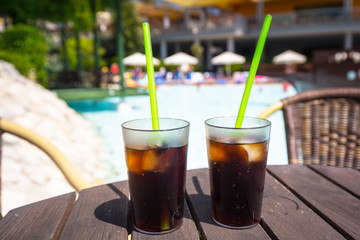 Glasses with cola and ice at the pool on summer holidays