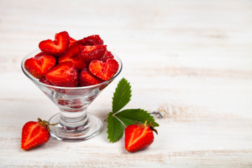 Strawberries  in a transparent bowl on a wooden table. Delicious berries.