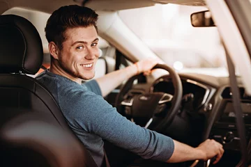 Foto op Canvas Happy young driver behind the wheel of a car. Buying a car and driving concept. © Mr. Music