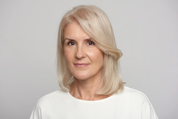 Closeup face of mature woman face isolated over grey background