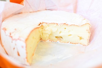 Close up of a Camembert cheese in the open original paper package.
