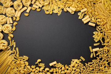 Assorted types of pasta on black background. Top view. Various forms of pasta. Copy space for design.