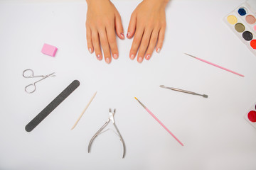 Nail care. beautiful women hands making nails on a white background. Women's hands near a set of professional manicure tools. Beauty care.Top view of manicure equipment.