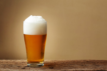 Glass beer on wooden table with cream wall background. copy space for design.