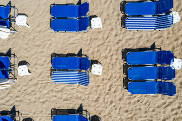 Summer umbrellas and sun beds on sandy beach. Sunbathing, relaxing and lying on the beach.
