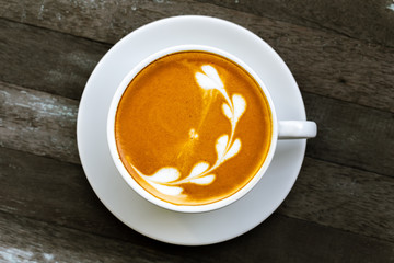 coffee cup with flower sign, top view on wooden table background.