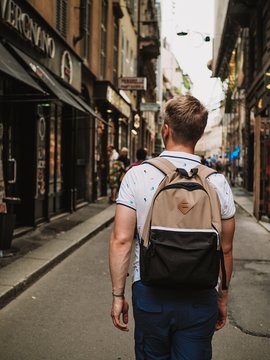 Young blond man with a backpack walking down the street in Milan