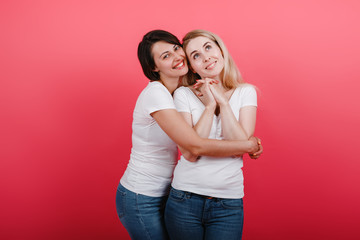 Two women embrace one another smiling and looking happy - Image