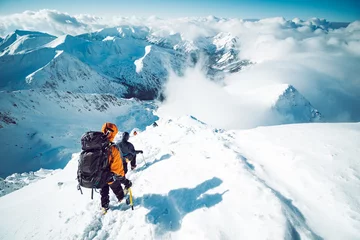 Tuinposter A group of climbers ascending a mountain in winter © kbarzycki