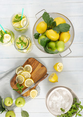 Citrus fruit drink concept. Fresh lemonade with apples and lemon on wooden table top view