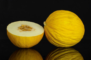 Group of one whole one half of fresh yellow melon canary isolated on black glass