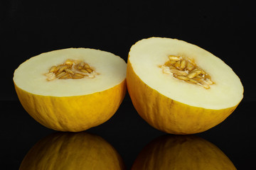 Group of two halves of fresh yellow melon canary one cut in two isolated on black glass