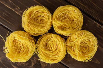 Group of five whole raw pasta angel hair flatlay on brown wood
