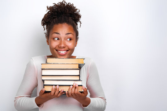 Portrait of happy nerd young girl holding books over white background. Back to school