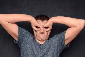 Portrait of funny man making mask of superhero with hands