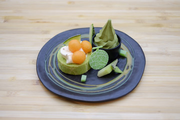 Hand hold plate of Melon japan rollcake with fresh melon slice and ice cream soft serve. selective focus