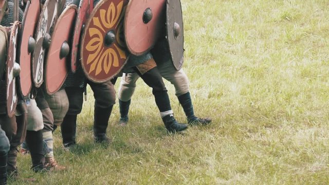 Knight warriors marching forward, shield wall. Medieval soldiers in full armor