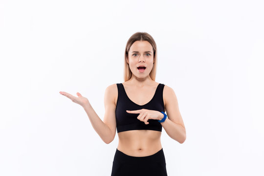 Young sporty blond woman in a black sportswear with smart watches for pulse measuring pointing with one hand at the pulm of a hand - Powered by Adobe
