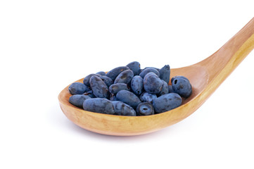 Haskap berries in a wooden spoon, isolated on white background