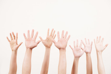 Close-up of crowd of young people stretching their arms up and voting together over white background