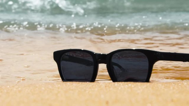Sunglasses on beach. Sea waves, sunny day. Concept of holiday, vacation, relaxation, day at seaside