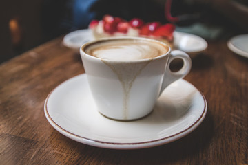 White cup of latte coffee with cake