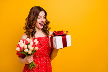 Beautiful foxy lady holding arms tulips bunch and big giftbox wear off-shoulders dress isolated yellow background