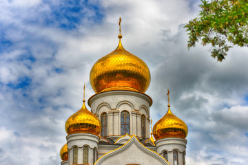 Orthodox Church, golden domes with crosses close-up against a blue cloudy sky, HDR photo.