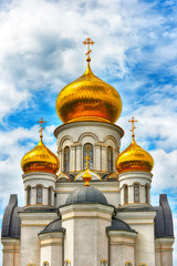 Fototapeta na wymiar Orthodox Church, golden domes with crosses close-up against a blue cloudy sky, HDR photo.