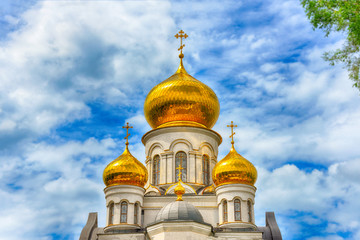 Fototapeta na wymiar Orthodox Church, golden domes with crosses close-up against a blue cloudy sky, HDR photo.