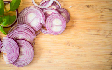 Red onion slices isolated on wooden chopping board