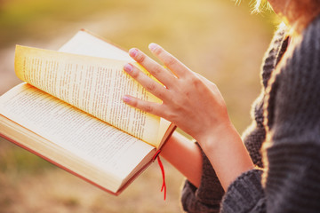 a girl reading a book in a meadow