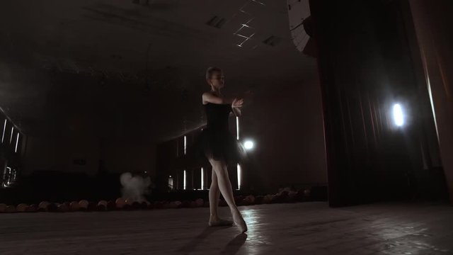 Prima ballerina on pointes training on stage with spotlights in late evening before important performance in Opera and Ballet theatre. Indoors