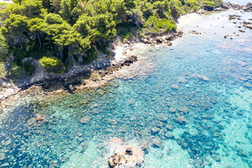 Aerial view of green seashore and turquoise sea water. Island with green trees in the ocean seen...