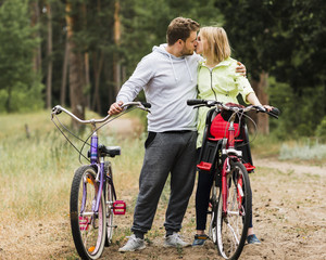 Fototapeta premium Couple kissing next to bikes on forest road