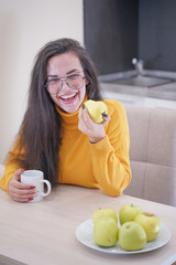 Close up portrait of a lovely pretty girl biting an apple in white kitchen background