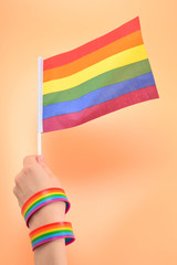 LGBT flag in woman hand on orange background. Copy space.