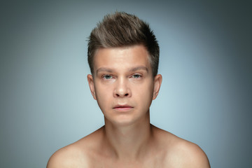 Portrait of shirtless young man isolated on grey studio background. Caucasian healthy male model looking at camera and posing. Concept of men's health and beauty, self-care, body and skin care.