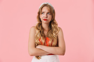 Image of upset young woman frowning and looking at copyspace with arms crossed
