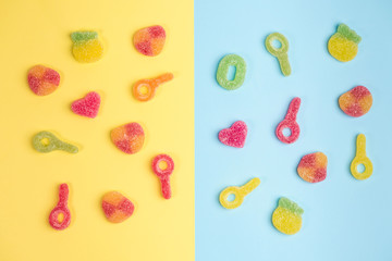 Multicolored gummy candies on yellow and blue backgrounds. Top view.