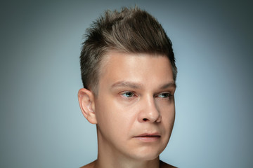 Fototapeta premium Portrait of shirtless young man isolated on grey studio background. Caucasian healthy male model looking at side and posing. Concept of men's health and beauty, self-care, body and skin care.