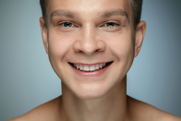 Obraz premium Portrait of shirtless young man isolated on grey studio background. Caucasian healthy male model looking at camera and smiling. Concept of men's health and beauty, self-care, body and skin care.